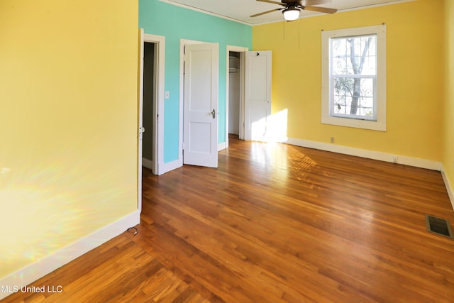 empty room with ceiling fan, dark hardwood / wood-style flooring, and crown molding