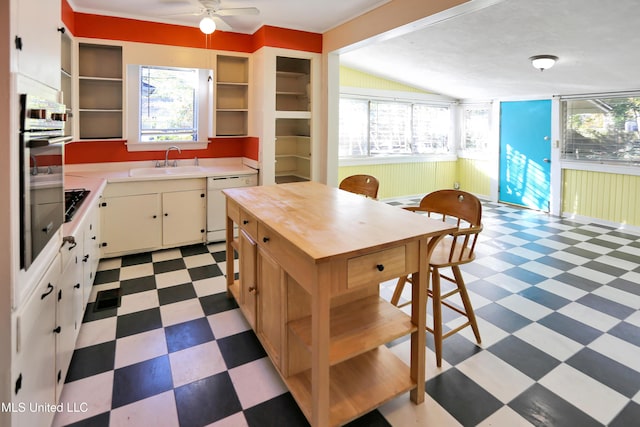 kitchen featuring dishwasher, stainless steel oven, lofted ceiling, sink, and ceiling fan