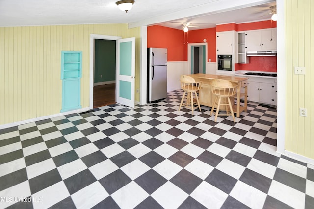 kitchen with white cabinets, oven, stainless steel fridge, cooktop, and a breakfast bar area