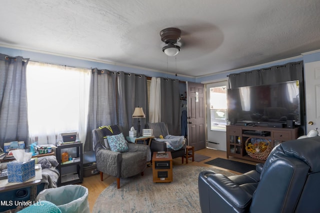 living area with a textured ceiling, a ceiling fan, and wood finished floors