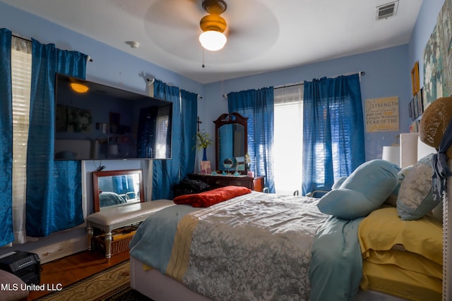 bedroom featuring ceiling fan, visible vents, and wood finished floors