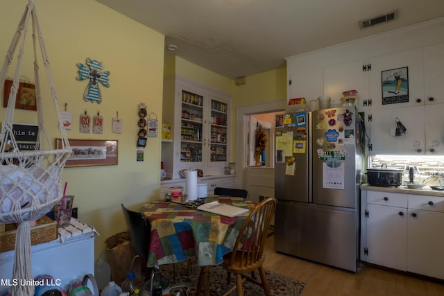 kitchen featuring light wood-style floors, visible vents, white cabinets, and freestanding refrigerator