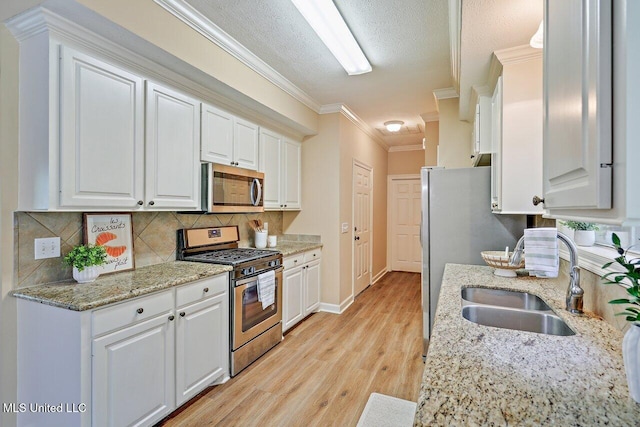 103 Cavitt Cv, Clinton, MS 39056 - kitchen featuring appliances with stainless steel finishes, a sink, light wood finished floors, white cabinets, and tasteful backsplash