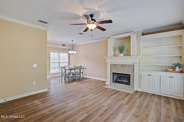 103 Cavitt Cv, Clinton, MS 39056 - living area featuring a ceiling fan, a chandelier, ornamental molding, wood finished floors, and a tiled fireplace