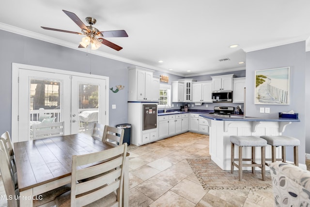 112 Vista Dr, Pass Christian, MS 39571 - kitchen with stainless steel appliances, a kitchen bar, white cabinetry, ornamental molding, and a peninsula