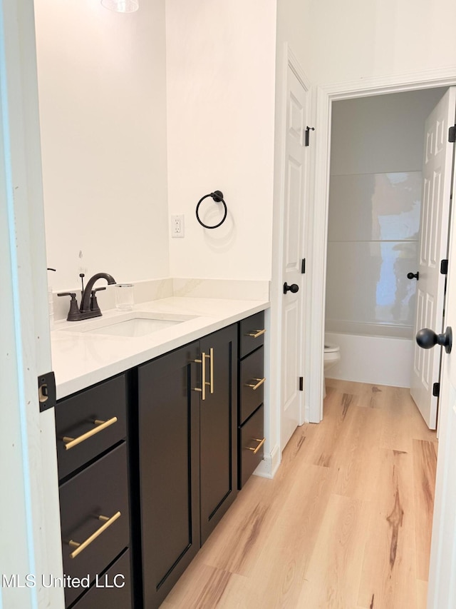 bathroom with wood finished floors, toilet, and vanity