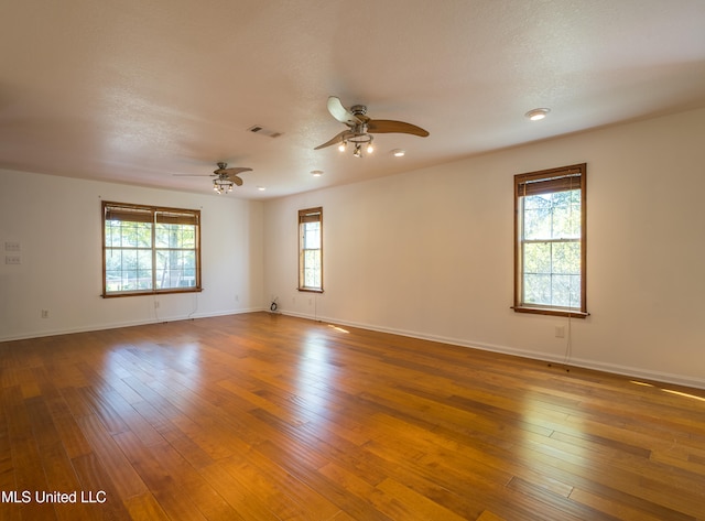 unfurnished room with a textured ceiling, dark wood-type flooring, and ceiling fan