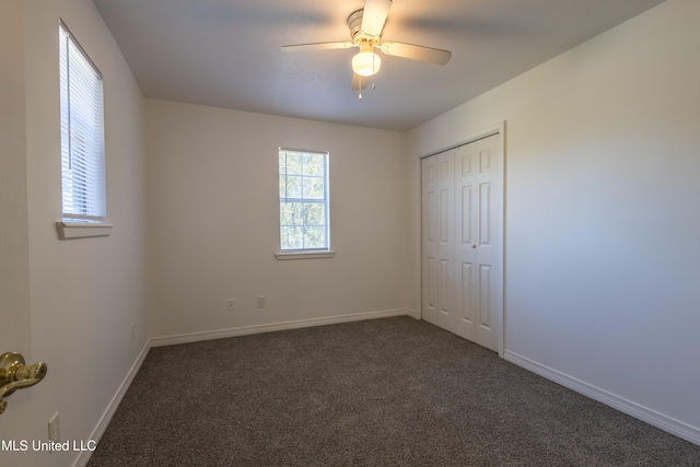 unfurnished bedroom featuring a closet, dark carpet, and ceiling fan