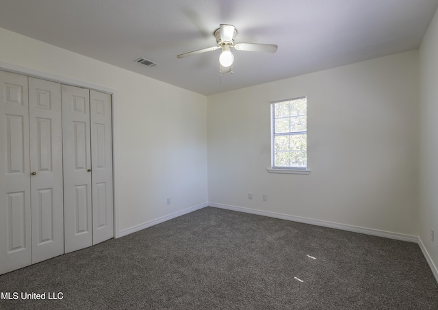 unfurnished bedroom featuring a closet, dark carpet, and ceiling fan