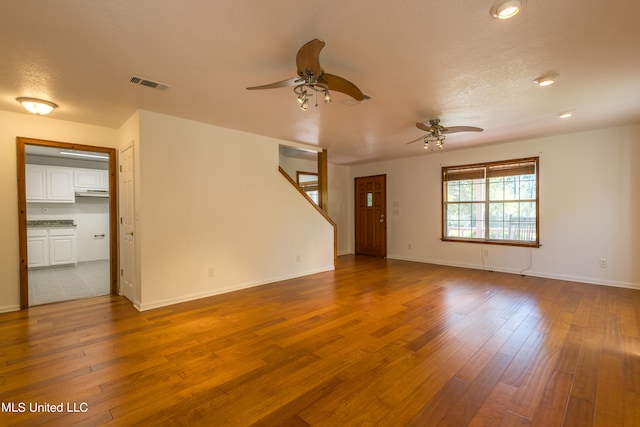 empty room featuring a textured ceiling, light wood-type flooring, and ceiling fan