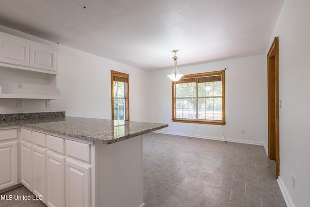 kitchen with kitchen peninsula, white cabinetry, stone countertops, and decorative light fixtures