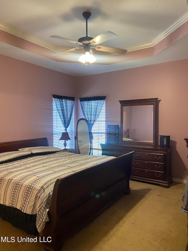 carpeted bedroom with ornamental molding, a tray ceiling, and ceiling fan