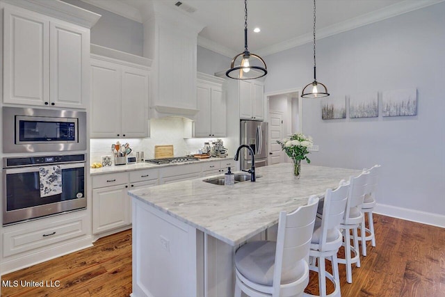 1235 Cutter Ln, Brandon, MS 39047 - kitchen with stainless steel appliances, a kitchen island with sink, crown molding, white cabinets, and a kitchen breakfast bar