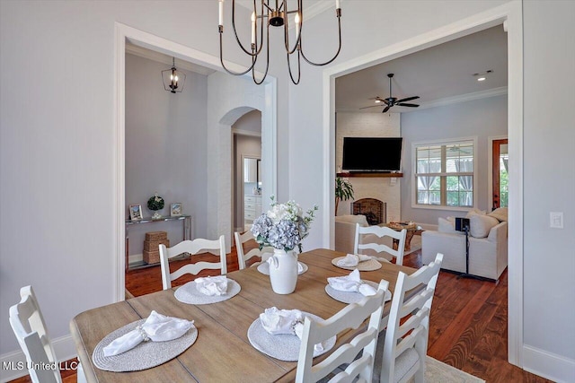 1235 Cutter Ln, Brandon, MS 39047 - dining area featuring arched walkways, a ceiling fan, dark wood finished floors, a brick fireplace, and ornamental molding