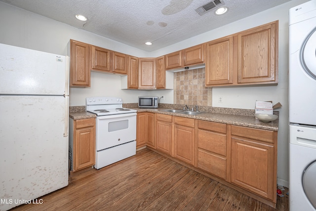 kitchen with stacked washing maching and dryer, a textured ceiling, light hardwood / wood-style floors, sink, and white appliances