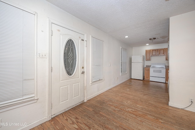 foyer entrance featuring a textured ceiling and light wood-type flooring