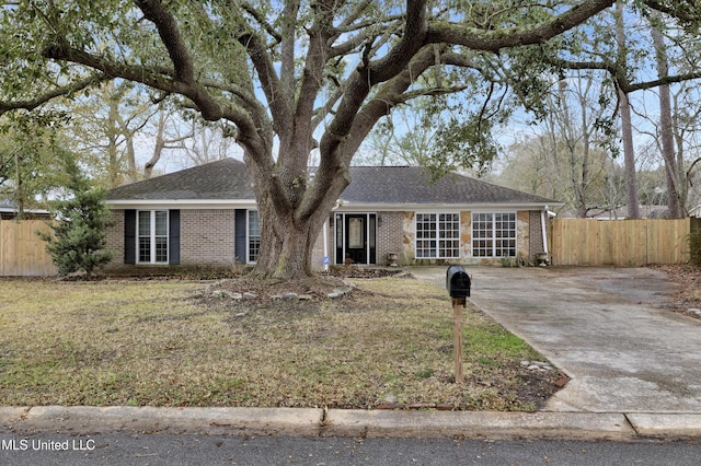 single story home with brick siding, fence, a front lawn, and roof with shingles