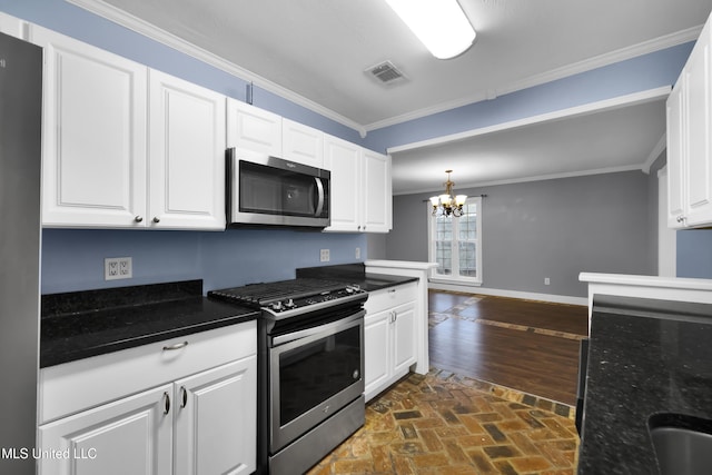 kitchen with brick floor, a notable chandelier, stainless steel appliances, visible vents, and crown molding