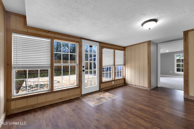 empty room with baseboards, a textured ceiling, and wood finished floors