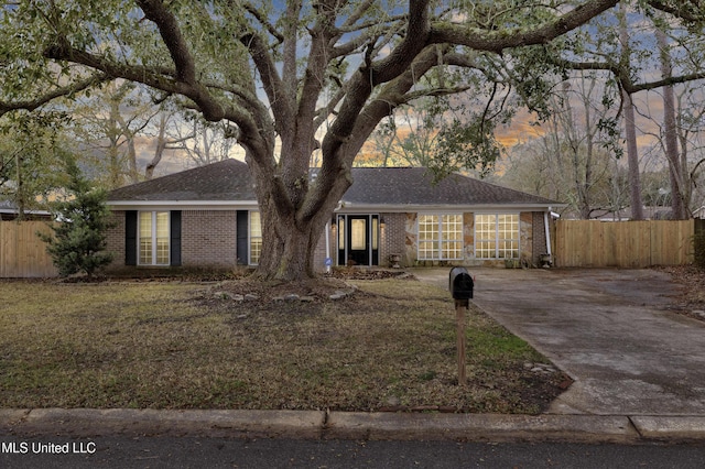 ranch-style home featuring a front yard, brick siding, and fence