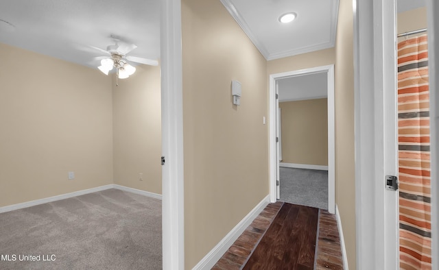 hallway featuring crown molding, baseboards, and carpet flooring