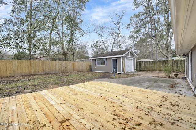 wooden terrace featuring an outbuilding, a fenced backyard, and a detached garage