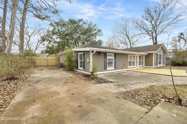 view of front facade featuring concrete driveway, a patio, cooling unit, and fence