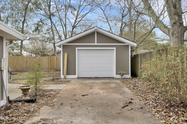 detached garage with concrete driveway and fence