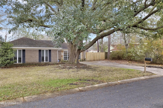 view of front of property featuring driveway, roof with shingles, fence, a front lawn, and brick siding