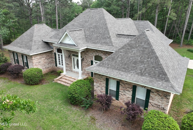 110 Frye Rd, Hattiesburg, MS 39401 - view of front of house with a front yard, brick siding, a shingled roof, and a view of trees