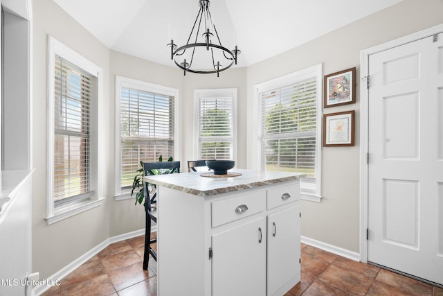kitchen featuring an inviting chandelier, baseboards, vaulted ceiling, and white cabinetry