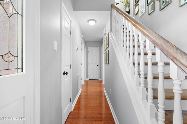 hall featuring baseboards, stairs, and wood finished floors
