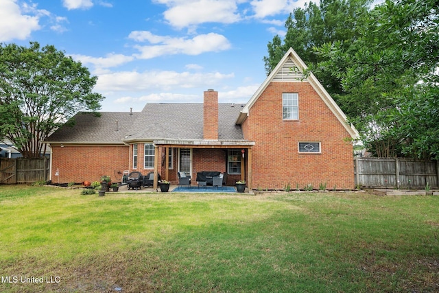 back of house with an outdoor living space, a lawn, a patio area, brick siding, and a fenced backyard