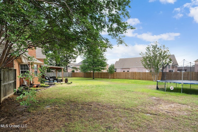 view of yard featuring a residential view, a fenced backyard, and a trampoline
