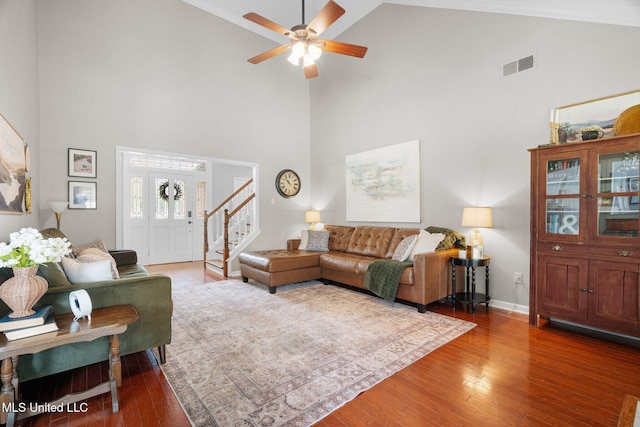 living area with a ceiling fan, visible vents, wood finished floors, stairway, and high vaulted ceiling