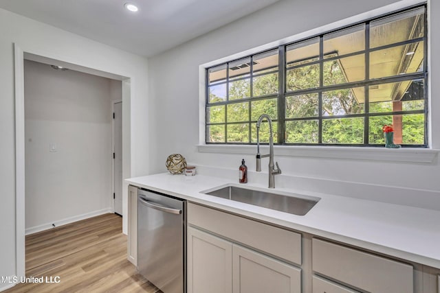 kitchen featuring a healthy amount of sunlight, sink, stainless steel dishwasher, and light hardwood / wood-style floors