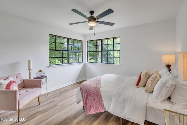 bedroom featuring ceiling fan, light hardwood / wood-style floors, and multiple windows