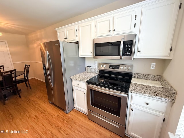 999 Hamakua St, Diamondhead, MS 39525 - kitchen featuring appliances with stainless steel finishes, white cabinetry, light wood-style flooring, and light stone counters