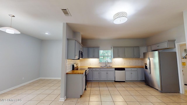 kitchen with gray cabinetry, sink, wood counters, stainless steel appliances, and decorative light fixtures