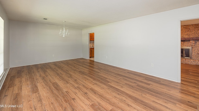 828 Briarwood Dr, Jackson, MS 39211 - unfurnished room featuring a chandelier, wood finished floors, a fireplace, and baseboards