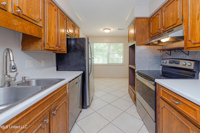828 Briarwood Dr, Jackson, MS 39211 - kitchen with appliances with stainless steel finishes, under cabinet range hood, brown cabinetry, and light tile patterned floors