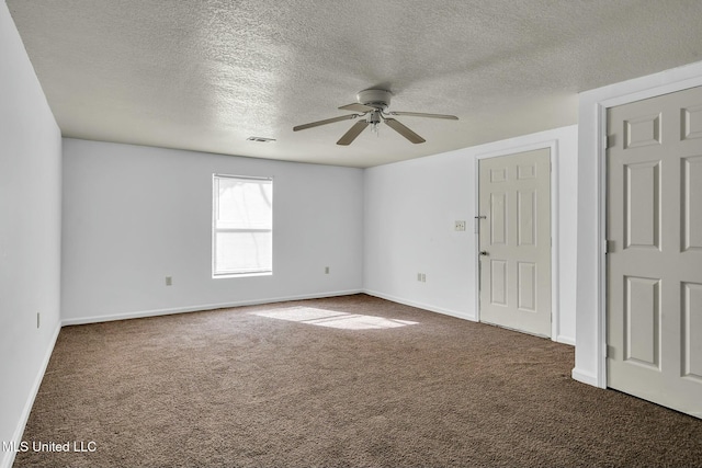 spare room featuring ceiling fan, dark carpet, and a textured ceiling