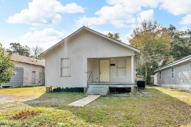 rear view of house featuring central AC and a lawn