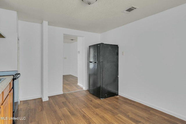 kitchen with black refrigerator, electric stove, and dark wood-type flooring