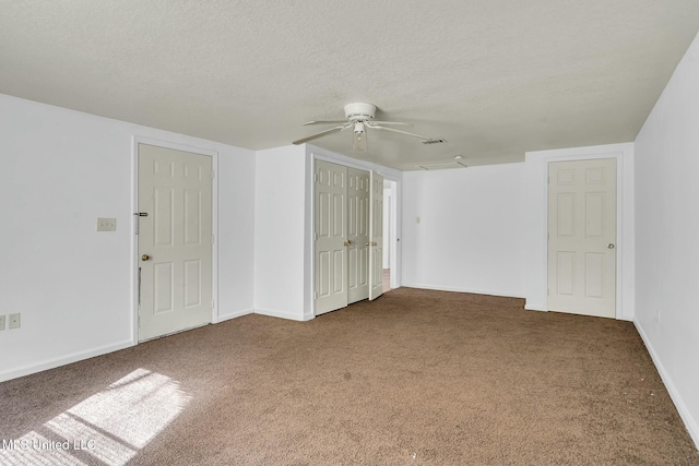 spare room featuring ceiling fan, dark carpet, and a textured ceiling