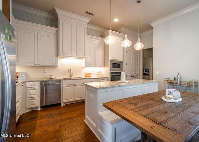 kitchen with a center island, sink, light stone countertops, white cabinetry, and stainless steel appliances