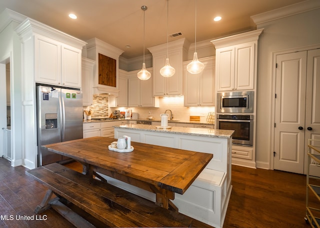 kitchen with light stone countertops, appliances with stainless steel finishes, tasteful backsplash, white cabinetry, and hanging light fixtures