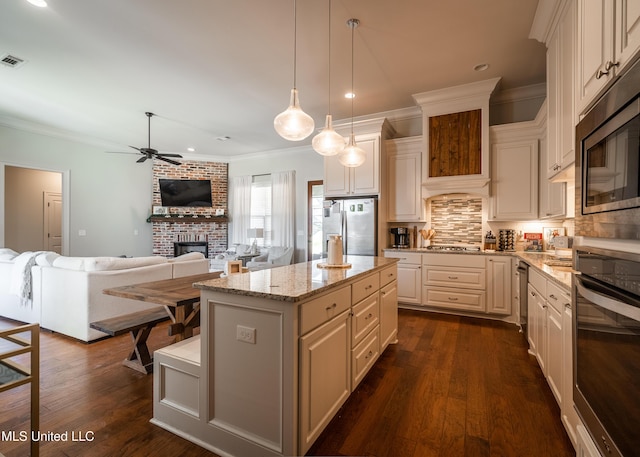 kitchen featuring pendant lighting, a center island, dark hardwood / wood-style floors, light stone countertops, and stainless steel appliances