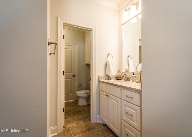 bathroom with vanity, toilet, and ornamental molding