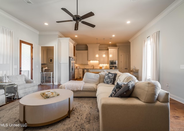 living room featuring hardwood / wood-style flooring, ceiling fan, ornamental molding, and sink